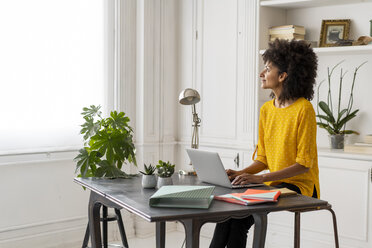 Woman sitting at desk, working, using laptop - AFVF02248