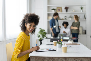 Frau bei der Arbeit im Coworking Space, im Hintergrund diskutieren Kollegen - AFVF02271