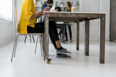 Frau bei der Arbeit im Coworking Space, im Hintergrund diskutieren Kollegen - AFVF02272