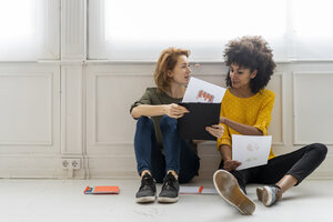 Colleagues in coworking space discussing business solutions, sitting on floor - AFVF02288