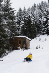 Austria, Tyrol, Thurn, happy mature woman sledding downhill - PSIF00211