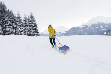 Österreich, Tirol, Thurn, Rückenansicht einer Schlitten ziehenden Frau in verschneiter Landschaft - PSIF00213