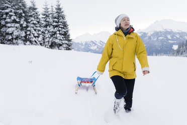 Austria, Tyrol, Thurn, mature woman pulling sledge in snow-covered landscape - PSIF00214