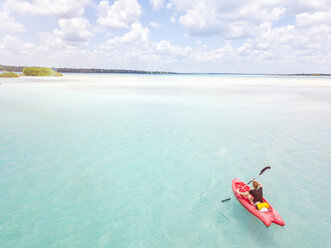 Mexiko, Yucatan, Quintana Roo, Bacalar, Frau im Kajak auf dem Meer in türkisfarbenem Wasser, Drohnenaufnahme - MMAF00774