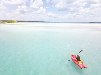 Mexiko, Yucatan, Quintana Roo, Bacalar, woman in kayak on the sea in turquoise water, drone image - MMAF00774