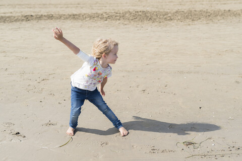 Verspieltes kleines Mädchen posiert am Strand, lizenzfreies Stockfoto