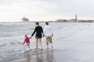 Italien, Caorle, zwei Frauen gehen mit Mädchen am Wasser spazieren - PSIF00219