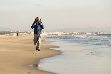 Spanien, Andalusien, Tarifa, Mann beim Wandern am Strand - KBF00402