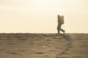 Man with backpack at the beach in the evening light - KBF00403