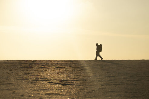 Man with backpack at the beach in the evening light - KBF00404