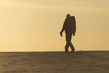 Mann mit Rucksack am Strand im Abendlicht - KBF00407