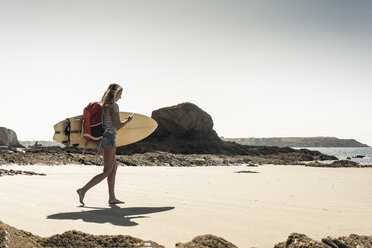 Junge Frau am Strand, mit Surfbrett, mit Smartphone - UUF16429