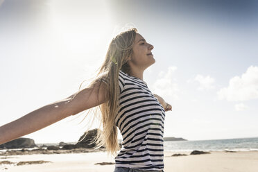 Glückliche junge Frau tanzt am Strand - UUF16442