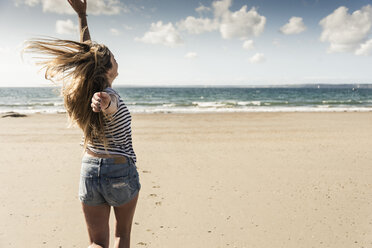 Glückliche junge Frau tanzt am Strand - UUF16443