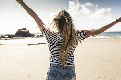 Glückliche junge Frau tanzt am Strand, lizenzfreies Stockfoto