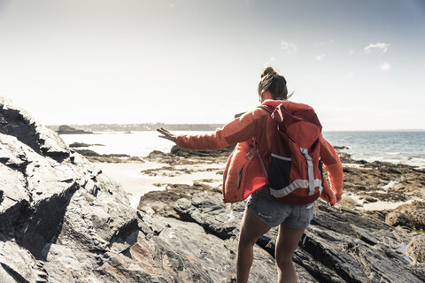 Junge Frau beim Wandern an einem felsigen Strand, lizenzfreies Stockfoto