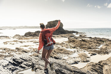 Young woman hiking on a rocky beach - UUF16451