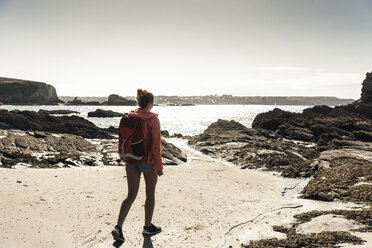Junge Frau beim Wandern an einem felsigen Strand - UUF16456