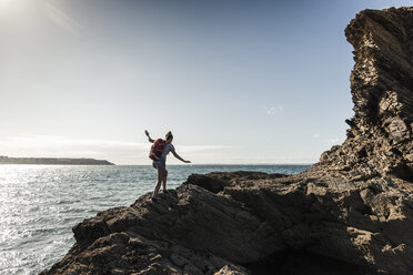 Junge Frau beim Wandern an einem felsigen Strand - UUF16460