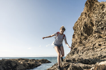 Junge Frau beim Wandern an einem felsigen Strand - UUF16466