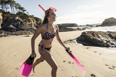 Happy young woman with snorkelling equipment, running on the beach - UUF16491