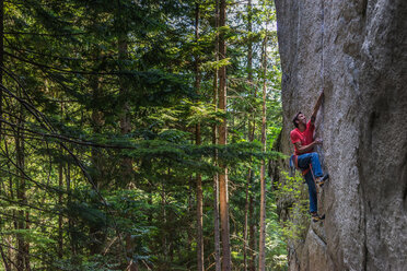 Rock climber scaling rock face close to trees, Squamish, Canada - CUF46922