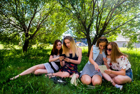 Freundinnen entspannen sich, nutzen intelligente Geräte im Stadtpark - CUF47065