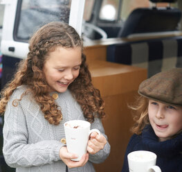 Mädchen trinken heiße Schokolade neben dem Wohnmobil - CUF47076