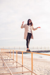 Woman walking on handrail at beach - CUF47079