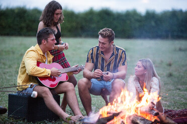 Junger Mann spielt Gitarre bei Lagerfeuerparty im Park - CUF47168