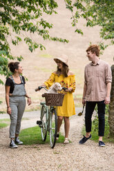 Friends taking walk with pushbike and pet dog in countryside - CUF47180