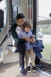 Vater und Sohn telefonieren in einer Straßenbahn - MAUF02286