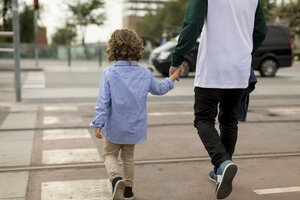 Rückansicht von Vater und Sohn, die Hand in Hand in der Stadt spazieren gehen - MAUF02294