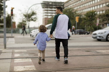 Rear view of father and son walking hand in hand in the city - MAUF02295