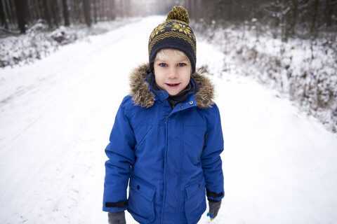 Porträt eines kleinen Jungen, der einen Spaziergang im Winterwald genießt, lizenzfreies Stockfoto