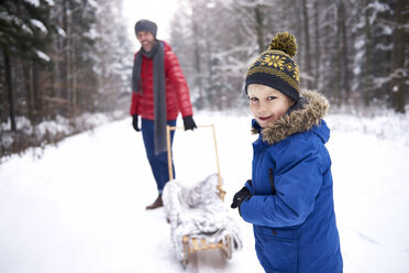 Portrait of smiling little boy in winter with his father and sledge - ABIF01127