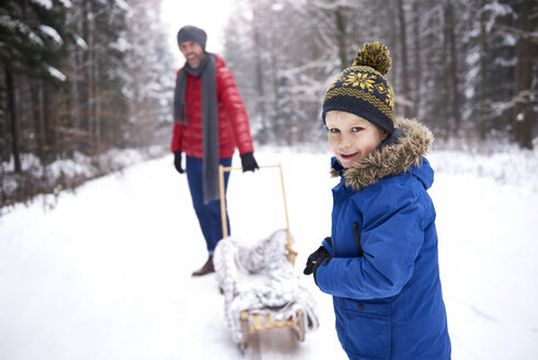 Porträt eines lächelnden kleinen Jungen im Winter mit seinem Vater und Schlitten - ABIF01127