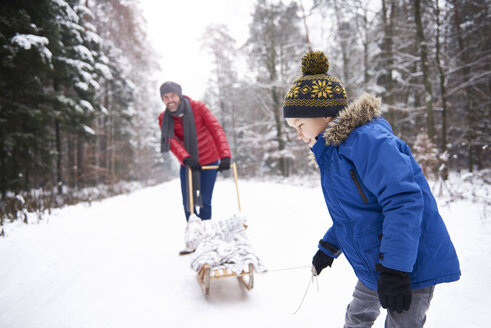 Kleiner Junge und sein Vater mit Schlitten im Winterwald - ABIF01129