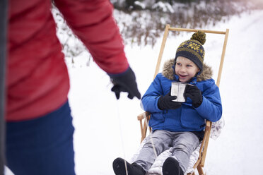 Portrait of smiling little boy drinking tea while his father pulling the sledge - ABIF01135