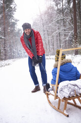 Father pulling sledge while looking at his son - ABIF01137