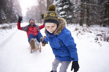 Little boy pulling his father sitting on sledge - ABIF01140