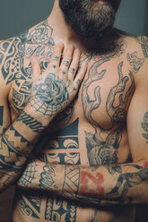 Bare chested young man, covered in tattoos, mid section - CUF47206