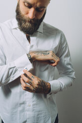 Bärtiger junger Mann mit weißem Hemd und Manschettenknöpfen, Tattoos an den Händen - CUF47214