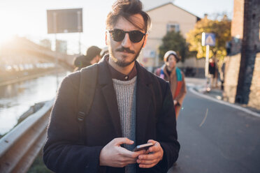 Man walking by canal, friends in background, Milan, Italy - CUF47228