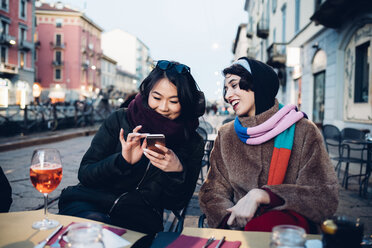 Friends enjoying drink at outdoor cafe, Milan, Italy - CUF47241