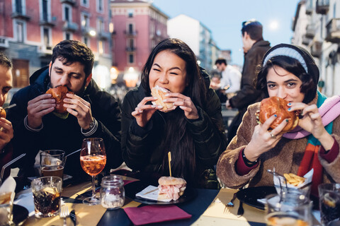 Friends enjoying burger at outdoor cafe, Milan, Italy stock photo