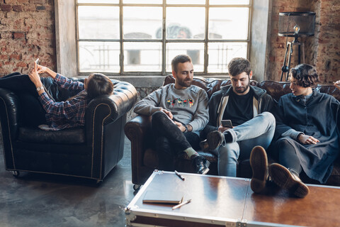 Designers taking break on sofa in studio stock photo