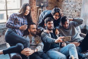 Group of colleagues on sofa taking selfie - CUF47267