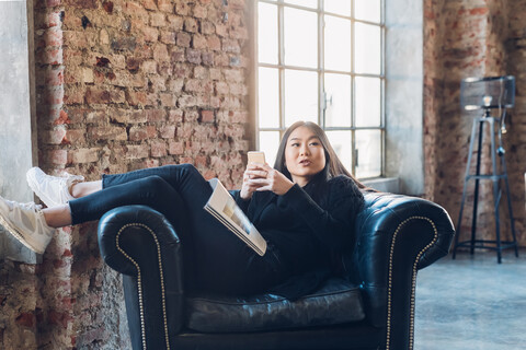 Frau auf Sessel mit Smartphone, lizenzfreies Stockfoto