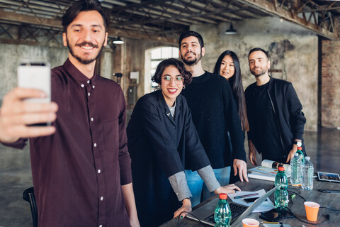 Designer and colleagues taking selfie at meeting table stock photo